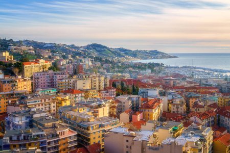 Panoramic view of Sanremo or San Remo from Pigna hill, Italian Riviera, Liguria, Italy. Scenic sunset landscape with city architecture, sea, green hills, blue water and sky, outdoor travel background