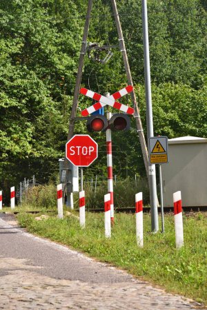Foto de Railway crossing on a forest road, the sign says not to touch the electric traction - Imagen libre de derechos
