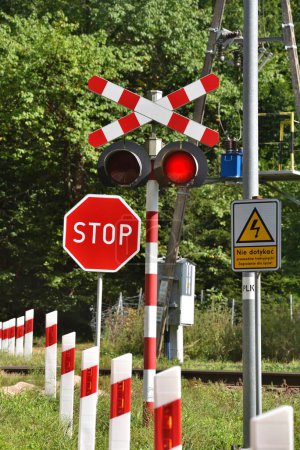 Foto de Railway crossing on a forest road, the sign says not to touch the electric traction - Imagen libre de derechos