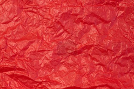 Crumpled paper background made from a blood red sheet of wrapping paper top view