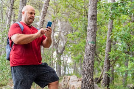 Photo for Portrait, smily man using the smartphone in the forest - Royalty Free Image