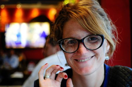 Portrait of young woman with eyeglasses in a bar