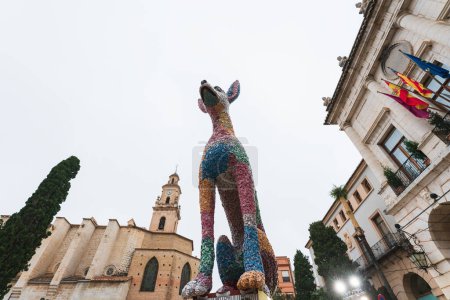 Foto de Gandia, Spain - 15 March 2022: 'Ninot' figurine dog in front of church, large paper mache statue, for the traditional celebration 'Fallas' on the main square - Imagen libre de derechos