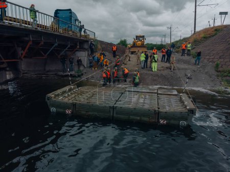 Téléchargez les photos : Pont de Ponton de l'armée ukrainienne. Installation d'un passage temporaire près du pont détruit. Soldats collectionnent ponton ferry. Vue de dessus depuis un drone. Nikopol, UKRAINE 26 mai 2020 - en image libre de droit