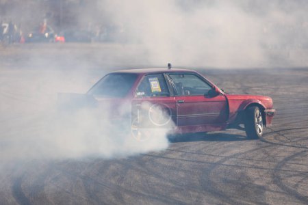 Photo for A racing car drifts on a fast track. The driver drifts the car. A car skidding against a background of smoke, smoking wheels. Speed. Extremesport. Route. DNIPRO, UKRAINE - March 30, 2024. - Royalty Free Image