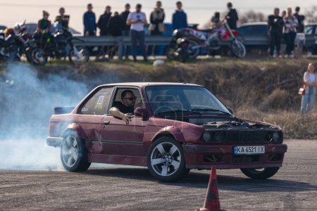 Photo for A racing car drifts on a fast track. The driver drifts the car. A car skidding against a background of smoke, smoking wheels. Speed. Extremesport. Route. DNIPRO, UKRAINE - March 30, 2024. - Royalty Free Image