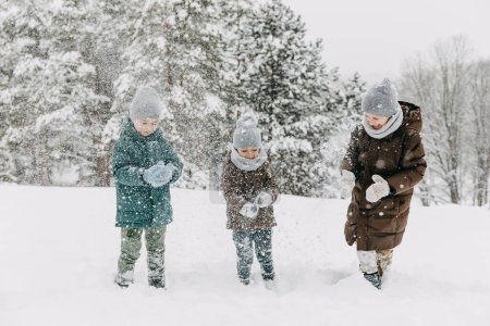 Photo for Children playing outdoors on winter day, shaking out snow from mittens. - Royalty Free Image