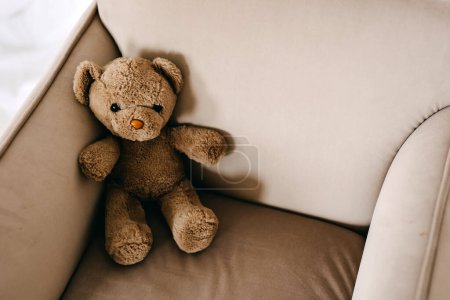 Photo for Old vintage brown teddy bear toy sitting in a small armchair. - Royalty Free Image