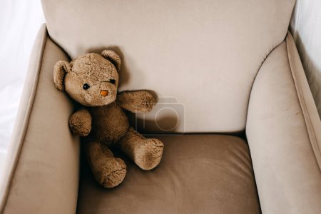 Photo for Old vintage brown teddy bear toy sitting in a small armchair. - Royalty Free Image