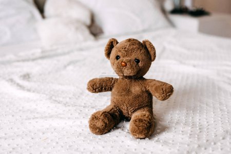 Photo for Old vintage brown teddy bear toy on a white blanket on bed. - Royalty Free Image