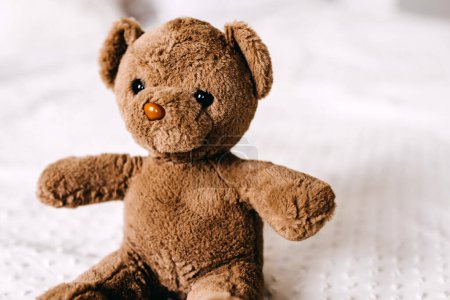 Photo for Old vintage brown teddy bear toy on a white blanket. - Royalty Free Image