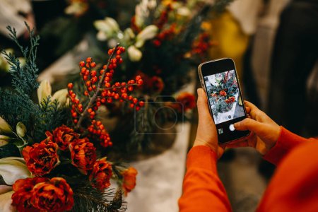 Foto de Mujer tomando fotos de una composición floral con un smartphone en un taller. - Imagen libre de derechos