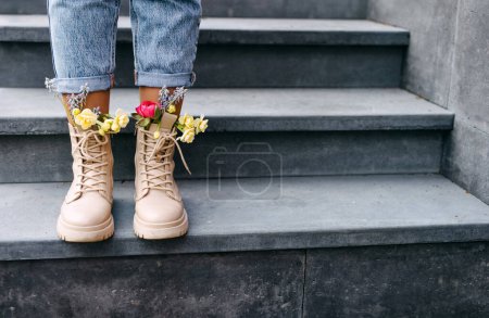 Photo for Female feet in boots with different colorful spring flowers inside. - Royalty Free Image