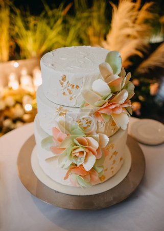 Photo for Three layered wedding cake decorated with flowers made of frosting. - Royalty Free Image