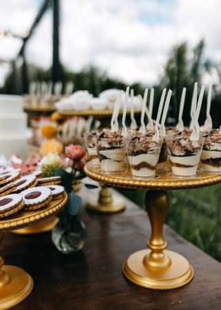 Téléchargez les photos : Un bar à bonbons à une fête. Table sucrée avec tiramisu et différents desserts faits main. - en image libre de droit