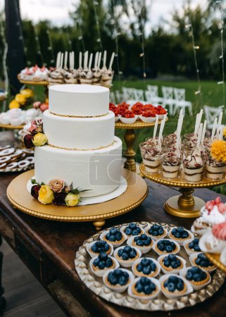 Photo for Candy bar at a wedding. Sweet table with wedding cake and different handmade desserts, outdoors. - Royalty Free Image
