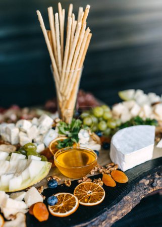 Photo for Buffet table with different cheese, honey, grapes and bread sticks at a party. - Royalty Free Image