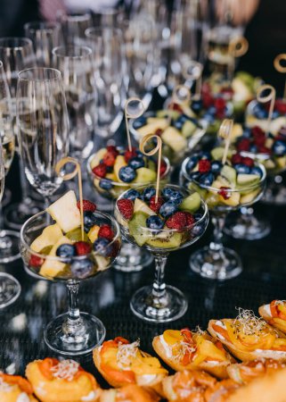 Foto de Mesa buffet con ensalada de frutas y copas de champán. - Imagen libre de derechos