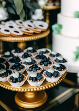 Foto de Un bar de dulces en una fiesta. Mesa dulce con cupcakes de arándanos y diferentes postres hechos a mano. - Imagen libre de derechos