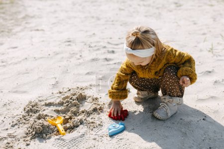 Foto de Niño jugando con moldes de arena y una pala en la playa. - Imagen libre de derechos