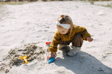 Foto de Niño jugando con moldes de arena y una pala en la playa. - Imagen libre de derechos