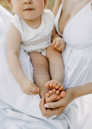 Photo for Mothers hand holding baby barefoot feet. - Royalty Free Image
