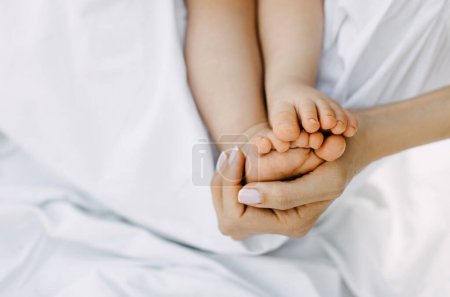 Téléchargez les photos : Gros plan de mères tenant bébé pieds nus. - en image libre de droit