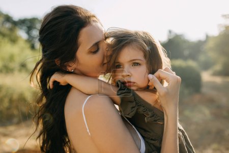 Photo for Closeup calm portrait of a mother holding her little sad daughter in arms, outdoors. - Royalty Free Image