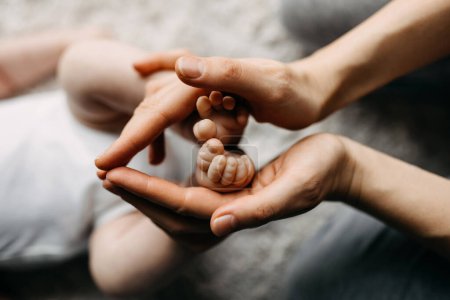 Téléchargez les photos : Les mains de la mère tenant les pieds d'un nouveau-né, symbolisant l'amour et les soins. - en image libre de droit