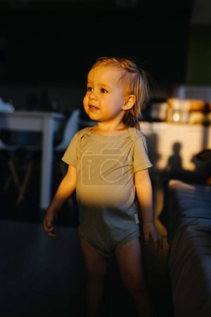 Photo for A young child in a green shirt, standing in direct sunlight. - Royalty Free Image