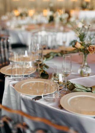 Foto de Una mesa de recepción de boda elegantemente establecida con platos, gafas y pañuelos textiles. - Imagen libre de derechos