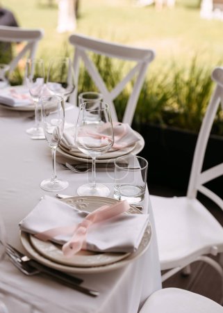 Téléchargez les photos : Une élégante table de réception de mariage avec des assiettes, des verres et des mouchoirs textiles. Mariage en plein air. - en image libre de droit