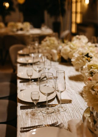 Foto de Una mesa de recepción de boda elegantemente establecida con platos, vasos y flores. - Imagen libre de derechos