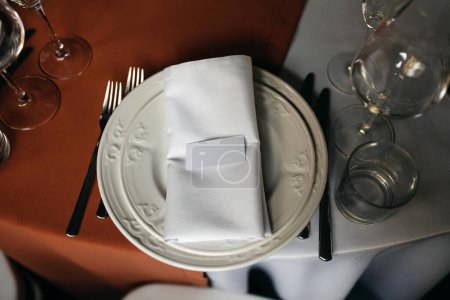 Photo for A top-down view of a wedding table setting with white plates, a folded napkin, and blank name card. - Royalty Free Image