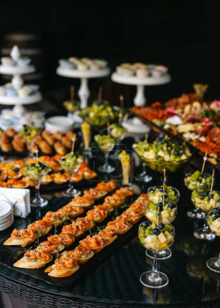 Photo for An array of gourmet appetizers displayed on a buffet, including salmon-topped crostini and fruit cups. - Royalty Free Image