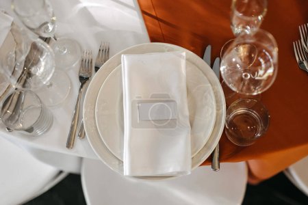 Foto de Una vista de arriba hacia abajo de una mesa de boda con platos blancos, una servilleta doblada y una tarjeta de nombre en blanco. - Imagen libre de derechos