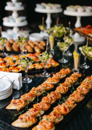 Foto de Una variedad de aperitivos gourmet exhibidos en un buffet, incluyendo crostini de salmón. - Imagen libre de derechos