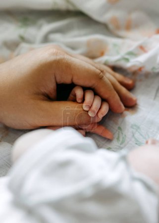 Photo for Closeup of father's hand holding a newborn small hand. - Royalty Free Image