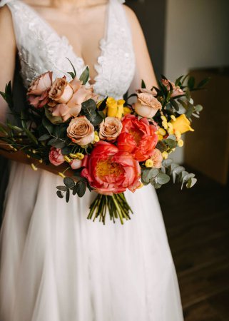 Téléchargez les photos : Une mariée tenant un bouquet de mariage avec un assortiment vibrant de fleurs. - en image libre de droit