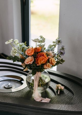 Photo for Bridal bouquet in glass vase on table with ribbon, near window. - Royalty Free Image