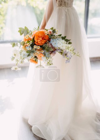 Téléchargez les photos : Mariée portant une robe blanche, tenant un bouquet floral vibrant. - en image libre de droit