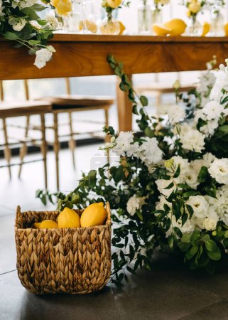 Foto de Elegancia rústica con limones en una cesta y flores blancas en flor. - Imagen libre de derechos