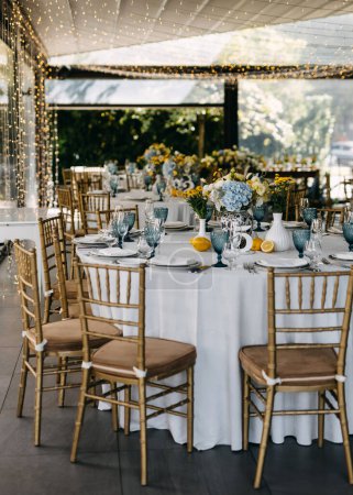 Foto de Elegante configuración de mesa con cristalería azul y acentos amarillos. Decoración de mesa de ambiente siciliano italiano en un restaurante. - Imagen libre de derechos