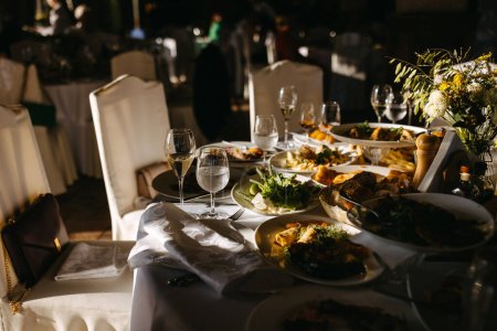 Festive banquet aftermath : table ensoleillée avec des restes d'un repas et du vin dans des verres.