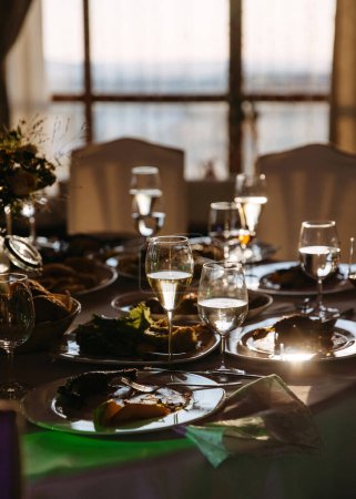 Photo for Festive banquet aftermath: sunlit table with remnants of a meal and wine in glasses. - Royalty Free Image