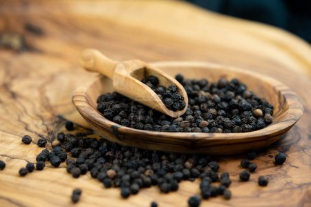 Photo for Many black peppercorns on olive wood - Royalty Free Image