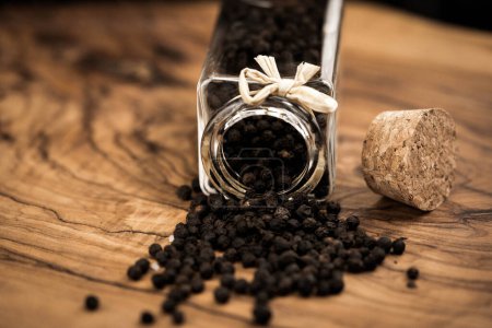 Photo for Many black peppercorns on olive wood - Royalty Free Image