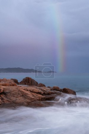 Long exposure of the Sardinian sea with silky waves and rainbow