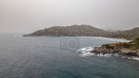Windiger Tag an einem Strand auf Sardinien. Hohe Wellen voller Wasser. Bewölkt