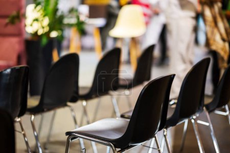 Las sillas de plástico negro se organizan en filas para los espectadores del seminario en la exposición. Fondo borroso. Foto de alta calidad